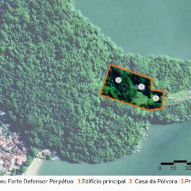 Vista aérea do terreno do Museu, composta majoritariamente pela paisagem natural e cercada pelo mar. Há uma linha laranja que delimita a área que abrange o edifício do museu, inserido nessa extensa área de vegetação. Indicado com o número 1, está o Edifício principal, número 2, a Casa da pólvora e número 3, a Praça de armas. A imagem inclui a legenda com a identificação das edificações, no canto inferior direito, a escala gráfica e, na parte superior esquerda, uma seta indicando o ponto cardeal norte.