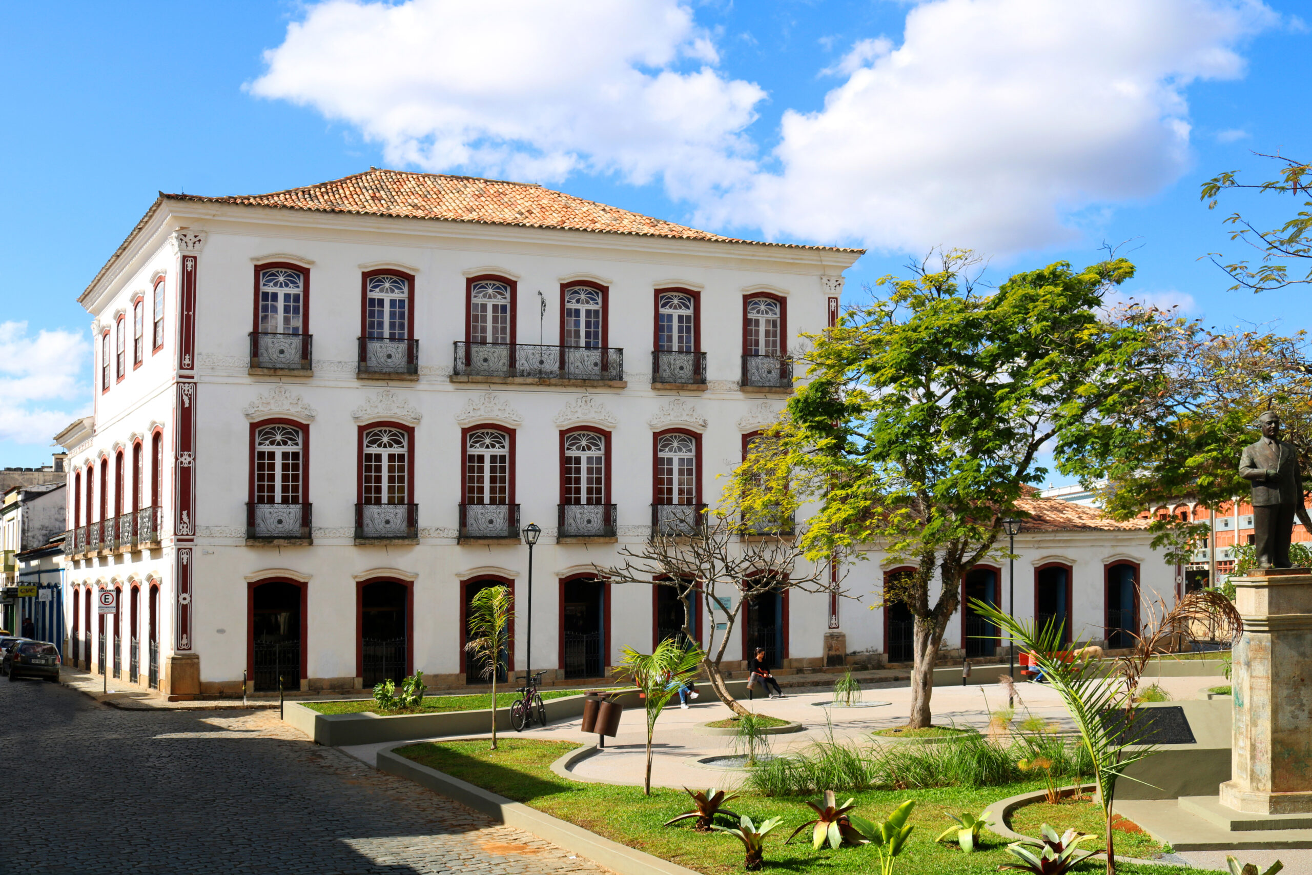 Fotografia do Museu, edifício de três pavimentos, de paredes brancas, esquadrias brancas com molduras de arcos na cor marrom. No térreo e nos demais pavimentos, apresenta portas com vergas em arco abatido. Há uma simetria entre os elementos, distribuídos tanto horizontalmente como verticalmente.